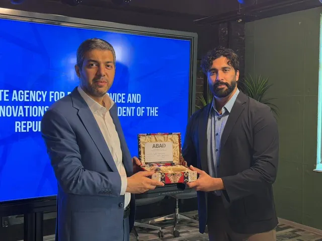 Two people holding a presentation gift in front of a blue ASAN agency display.