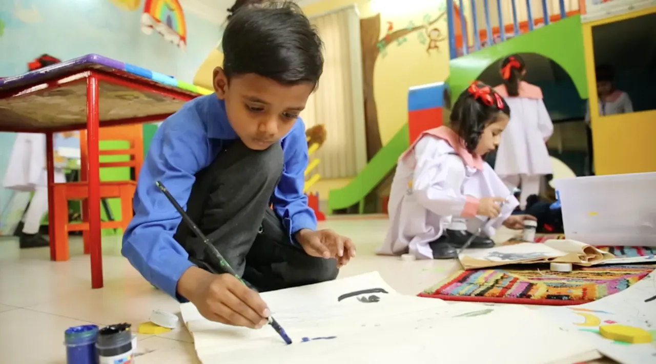 Children painting on paper in a classroom.